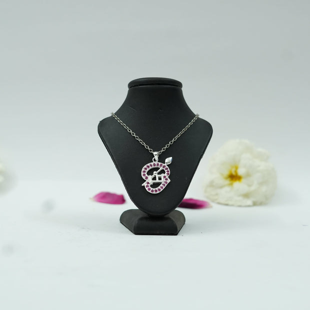 My Guru Ji Tamil Om pendant with silver finish and pink stone accents displayed on a black jewelry stand