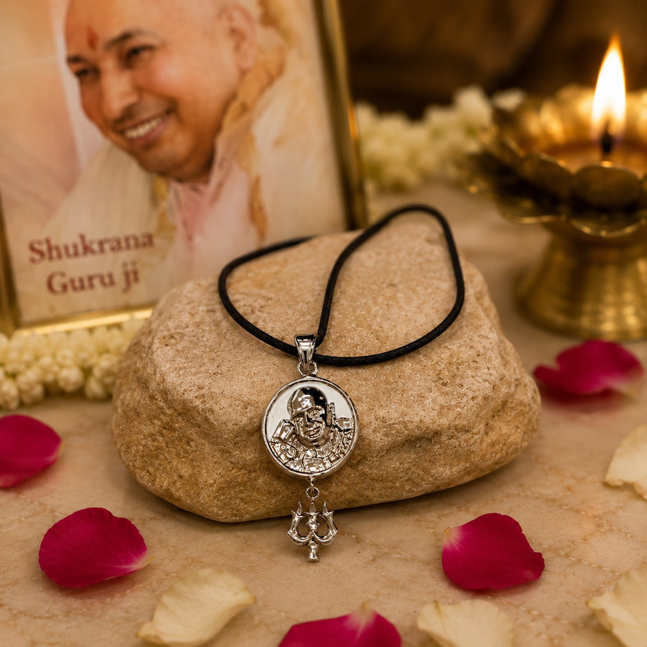 My Guru Ji silver finish brass pendant with Trishul charm and Guru Ji portrait, displayed on a stone with rose petals.